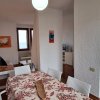 Sala da pranzo con tavolo apparecchiato, cucina sullo sfondo.
