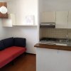 Cucina con salotto, divano rosso e pensili bianchi.