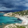Spiaggia con acque turchesi e cielo nuvoloso.
