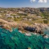 Costa rocciosa con mare blu e insediamenti collinari.