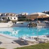 Piscina con lettini e ombrelloni, edifici sullo sfondo.