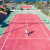 Campo da tennis rosso all'aperto con due persone che giocano.