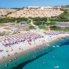Spiaggia affollata con ombrelloni e mare azzurro.