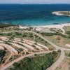 Vista dall'alto di una costa sabbiosa e mare blu.
