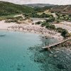 Spiaggia sabbiosa con sdraio e passerella sul mare.