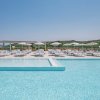 Piscina luminosa con lettini e ombrelloni bianchi.