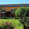 Struttura a tre piani con palme e arbusti nel giardino.