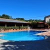Piscina all'aperto con aree coperte e palme.