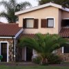 Casa con tetto in tegole e palme intorno.