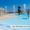 Piscina con fontane e ombrelloni sullo sfondo.