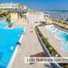 Piscina e spiaggia con ombrelloni.