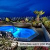 Piscina illuminata di notte, piante intorno.