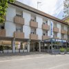 Facciata di un edificio bianco a quattro piani con balconi e una terrazza coperta.