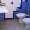 Bagno con piastrelle blu, lavandino e bidet.