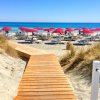 Spiaggia con ombrelloni rossi e mare azzurro.