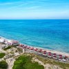 Vista dall'alto della spiaggia con ombrelloni rossi.