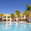 Piscina con palme e edificio giallo sullo sfondo.