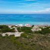 Spiaggia con mare turchese e cabine bianche e rosa.