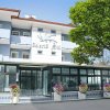 Facciata di un hotel bianco con balconi e un grande albero davanti.