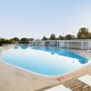 Piscina grande con lettini, cielo limpido.