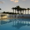 Piscina al tramonto, palme sullo sfondo.