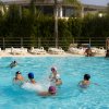 Bambini che giocano in piscina con cuffie colorate.