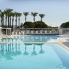 Piscina ampia circondata da palme e lettini.