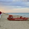 Un pattino rosso su una spiaggia con ombrelloni chiusi.