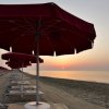 Ombrelloni rossi al tramonto su una spiaggia deserta.