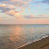 Spiaggia al tramonto con cielo nuvoloso e mare calmo.