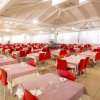 Sala pranzo con tavoli apparecchiati e sedie rosse.