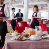 Camerieri servono colazione su tavoli apparecchiati.