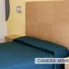 Letto matrimoniale con copriletto verde in camera.
