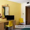 Scrivania con TV e sedia gialla in camera.