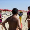 Gioco delle freccette su una spiaggia con ombrelloni rossi.