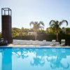 Piscina azzurra con palme e sdraio bianche.