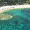 Vista aerea di una spiaggia con mare turchese e ombrelloni.