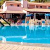 Piscina con ponticello e ombrelloni blu, albergo sullo sfondo.