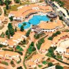 Vista aerea di un complesso alberghiero con piscine e tetti arancioni.