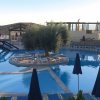 Piscina curvilinea con lettini e ombrelloni blu.