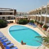 Piscina con lettini blu e edificio bianco.