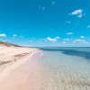 Spiaggia con sabbia chiara e mare trasparente.