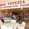 Ingresso di un bar ristorante con tavoli e sedie all'aperto.