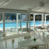 Sala con tavoli bianchi e vista su una piscina.