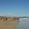 Spiaggia con molte persone e mare mosso.