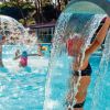 Bambini giocano in piscina con giochi d'acqua.