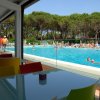 Vista di una piscina affollata da un'area con tavoli colorati.