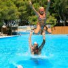Persona lancia in aria una bambina in una piscina.