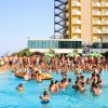 Persone in piscina affollata vicino a un hotel.