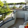Balcone con vista su alberi e mare, tavolo con frutta.